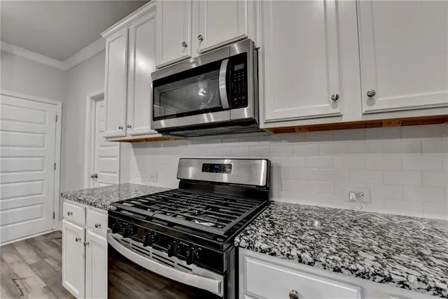 a kitchen with stainless steel appliances kitchen island granite countertop a sink stove and microwave