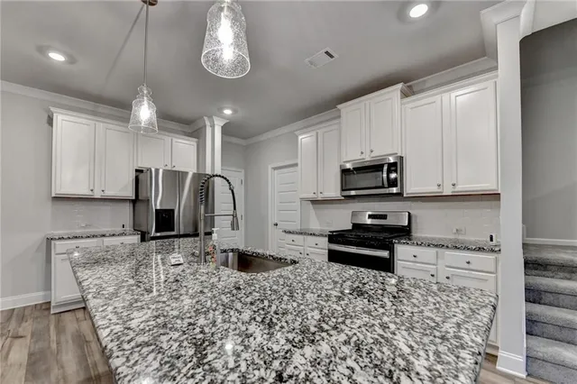 a kitchen with stainless steel appliances granite countertop a stove a sink and a microwave