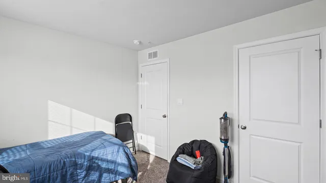 a bedroom with a bed and a dresser next to a white cabinet