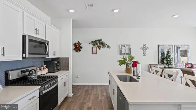 a kitchen with granite countertop a stove a sink dishwasher and a refrigerator with wooden floor