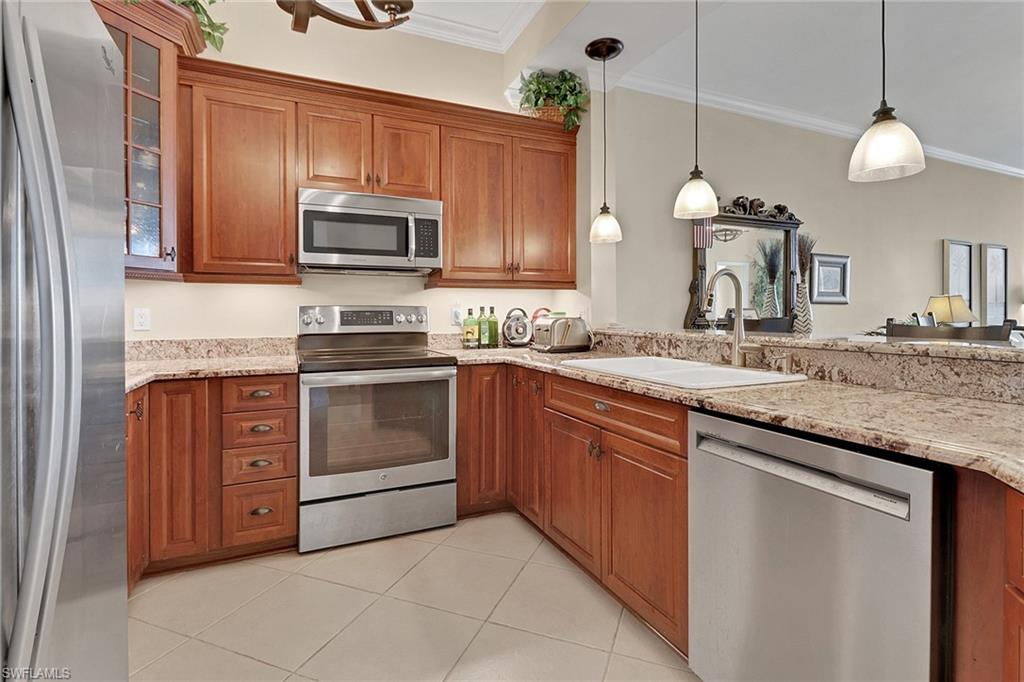 450 Bayfront Place, Unit 4509 Naples, FL 34102 - Photo 6 of 24 Kitchen featuring brown cabinetry, appliances with stainless steel finishes, pendant lighting, crown molding, and light tile patterned flooring