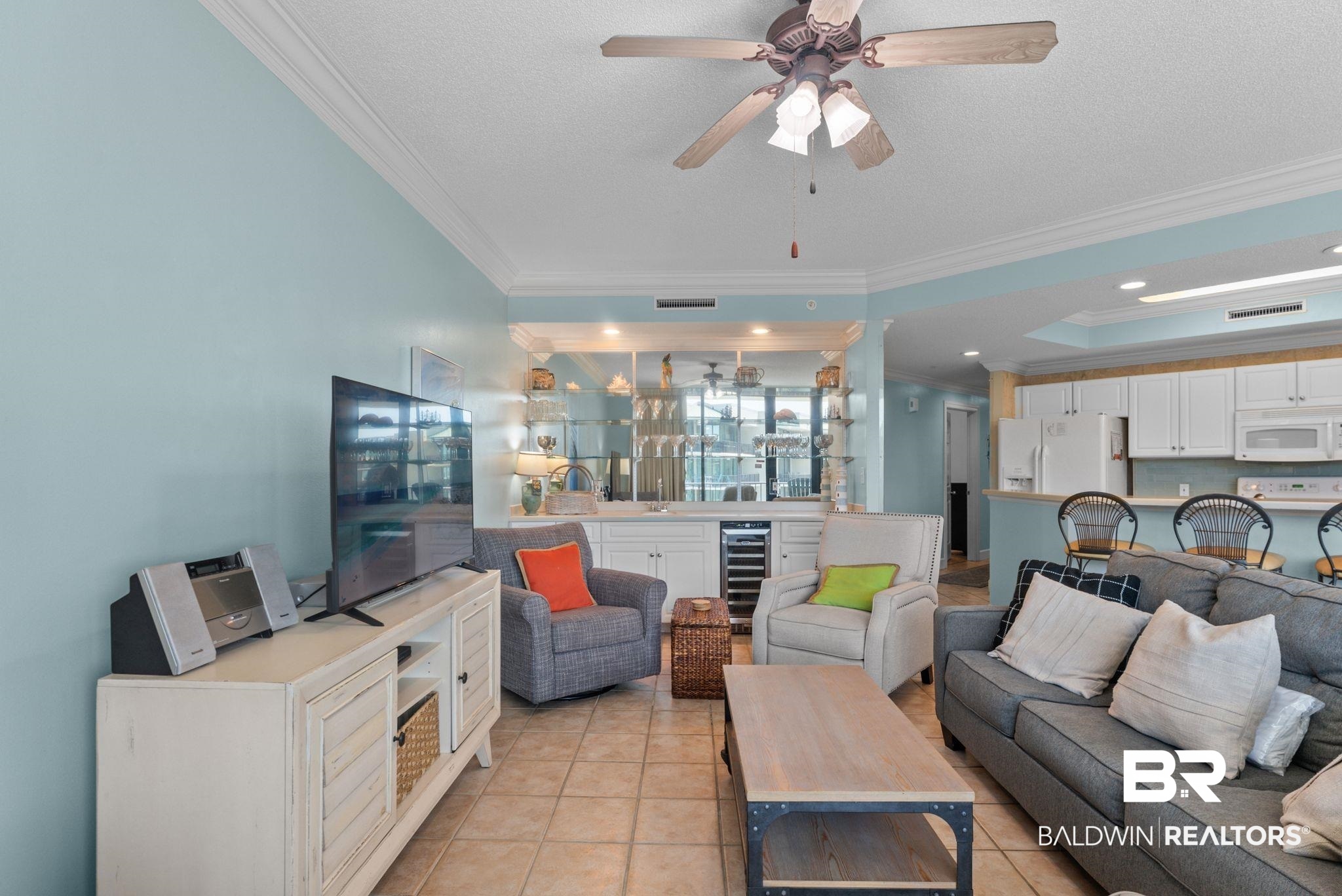 27580 Canal Road, Unit 1427 Orange Beach, AL 36561 - Photo 14 of 38 Living area featuring crown molding, wine cooler, ceiling fan, light tile patterned floors, and a tray ceiling