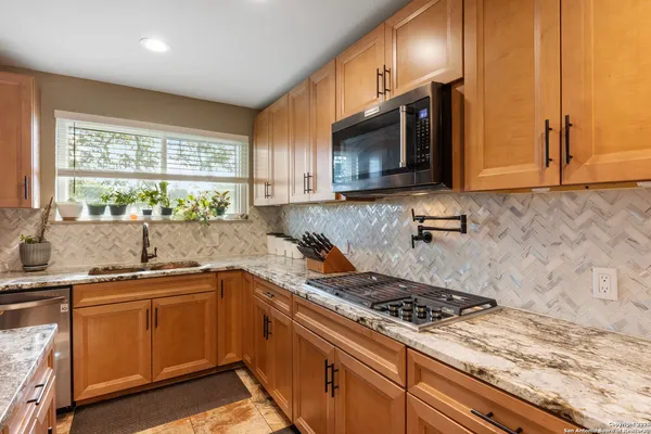 a kitchen with stainless steel appliances a sink a stove cabinets and a window