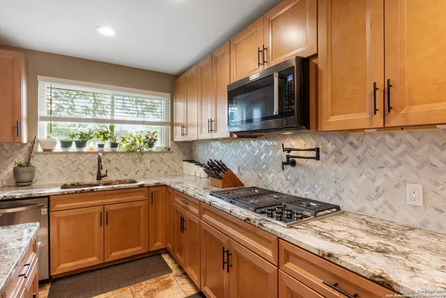 a kitchen with stainless steel appliances a sink a stove cabinets and a window
