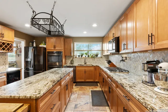 a kitchen with stainless steel appliances granite countertop a sink a stove top oven a counter space and cabinets