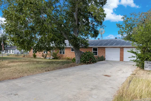 a front view of a house with a garden and tree