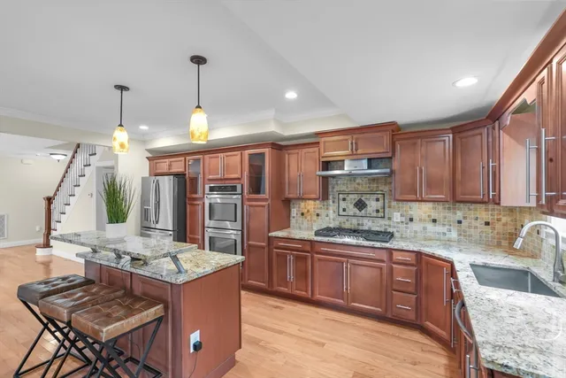 a kitchen with kitchen island granite countertop a stove a sink a refrigerator and a wooden cabinets