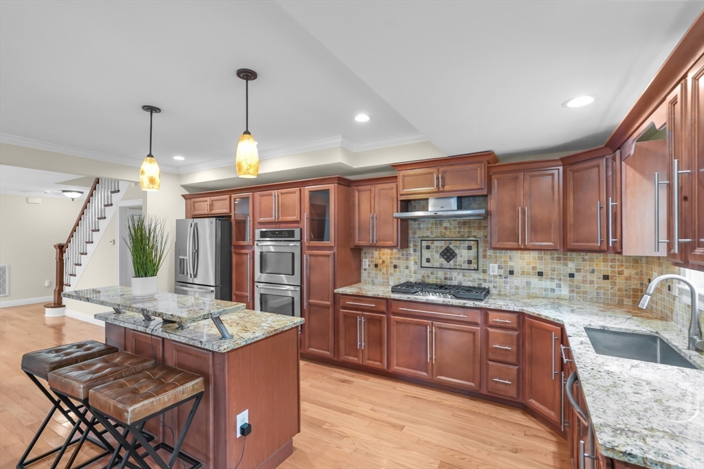 51 Faxon Street Braintree, MA 02184 - Photo 6 of 31 a kitchen with kitchen island granite countertop a stove a sink a refrigerator and a wooden cabinets