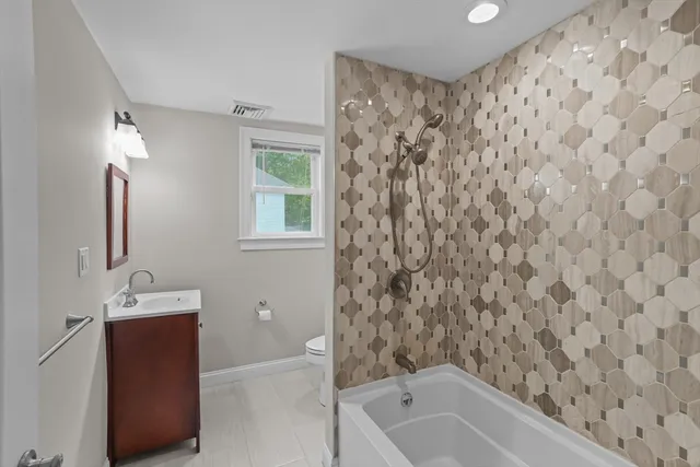 a bathroom with a bathtub sink vanity and toilet