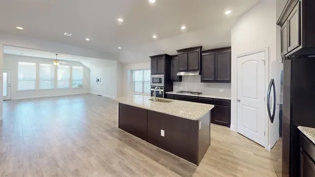 a large kitchen with stainless steel appliances granite countertop a sink a stove a refrigerator and cabinets