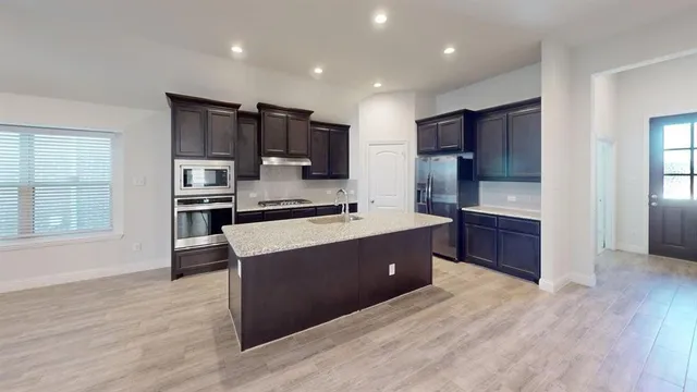 a large kitchen with stainless steel appliances kitchen island granite countertop a refrigerator and a stove top oven