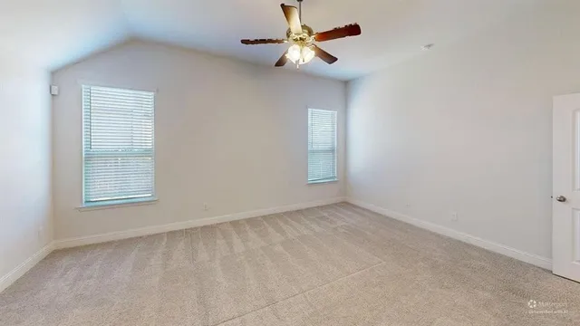an empty room with windows and fan