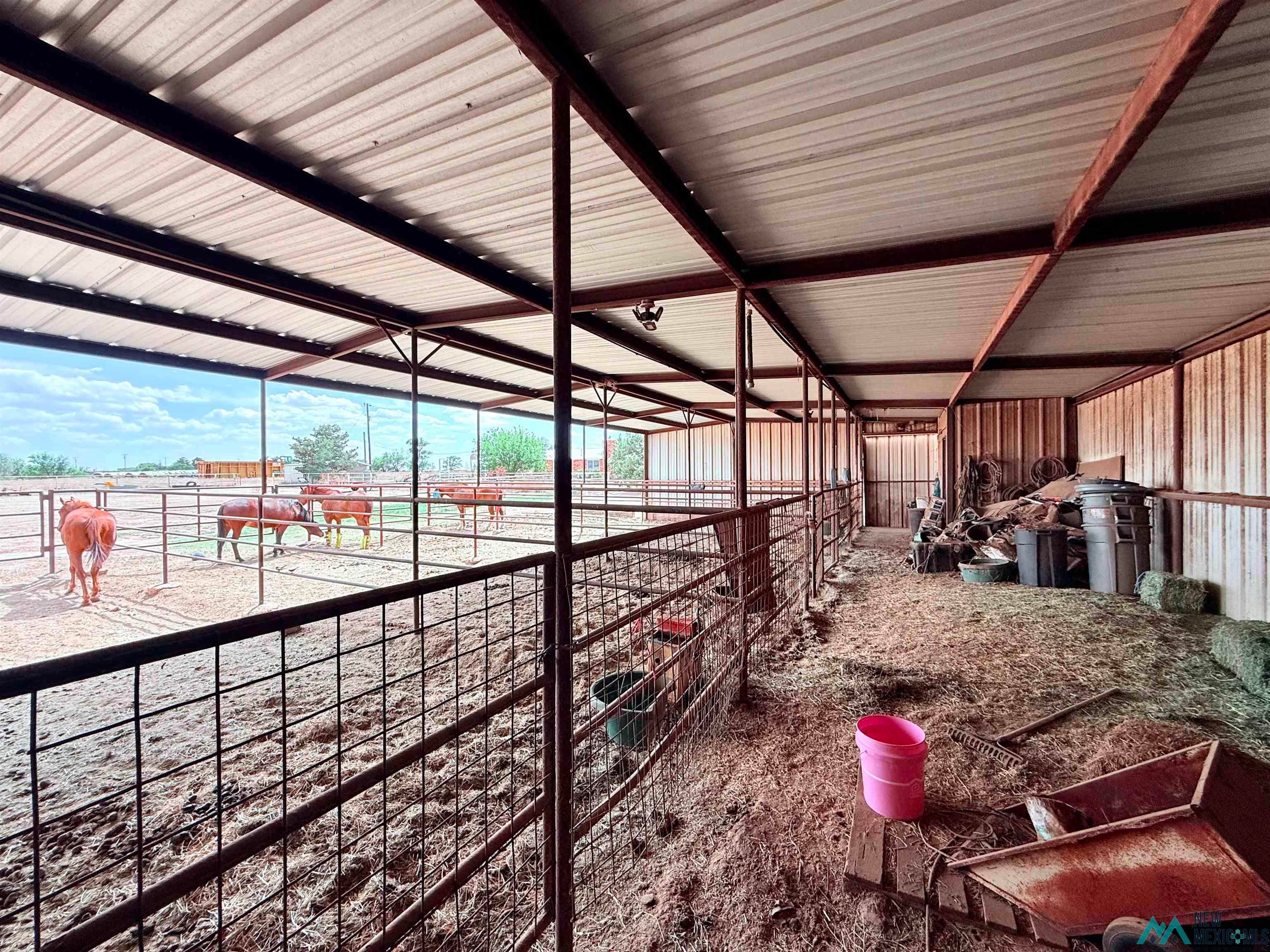 997 State Rte 108 Texico, NM 88135 - Photo 25 of 33 Covered livestock pens featuring a metal roof structure, open-air fencing, and a combination of dirt and hay flooring