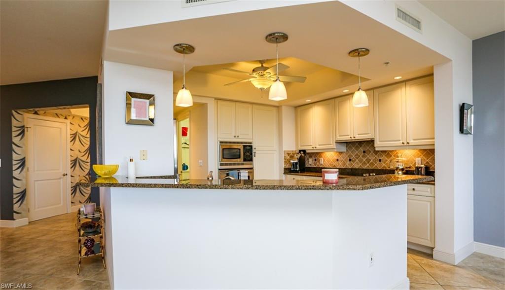 1060 Borghese Lane, Unit 603 Naples, FL 34114 - Photo 36 of 50 Kitchen with visible vents, stainless steel appliances, tasteful backsplash, a raised ceiling, and dark stone countertops