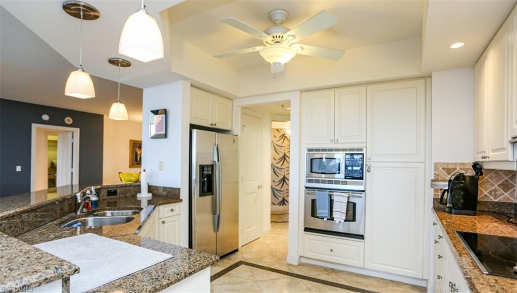 1060 Borghese Lane, Unit 603 Naples, FL 34114 - Photo 41 of 50 Kitchen featuring white cabinetry, decorative light fixtures, decorative backsplash, a sink, and appliances with stainless steel finishes