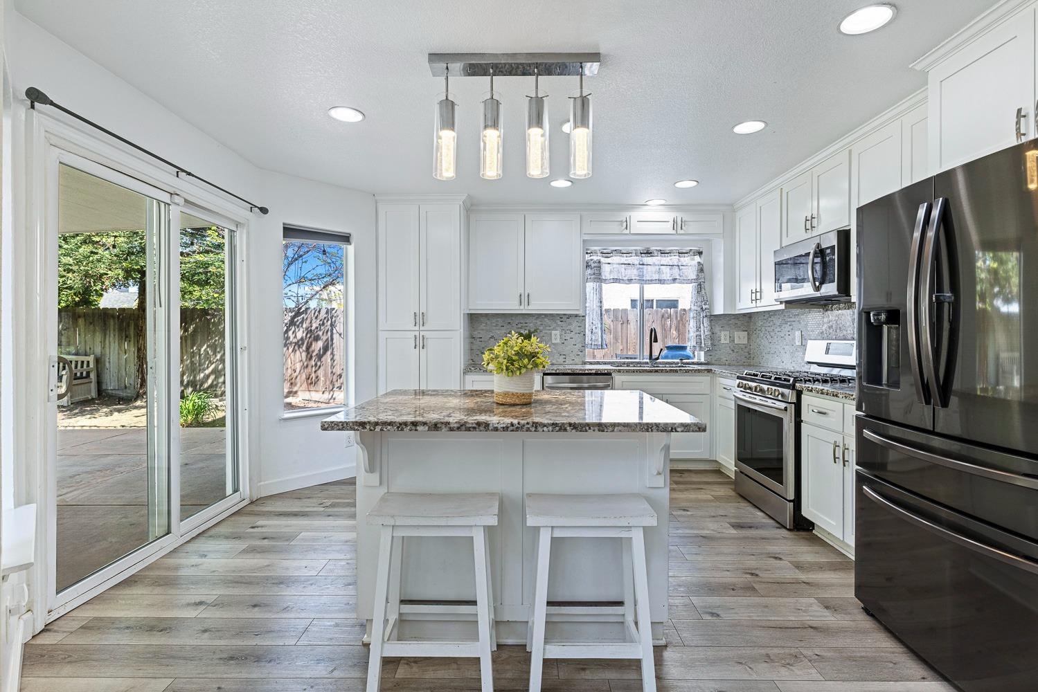 3232 Greenfield Avenue Clovis, CA 93611 - Photo 12 of 38 a kitchen with granite countertop a center island stainless steel appliances cabinets and a counter top space