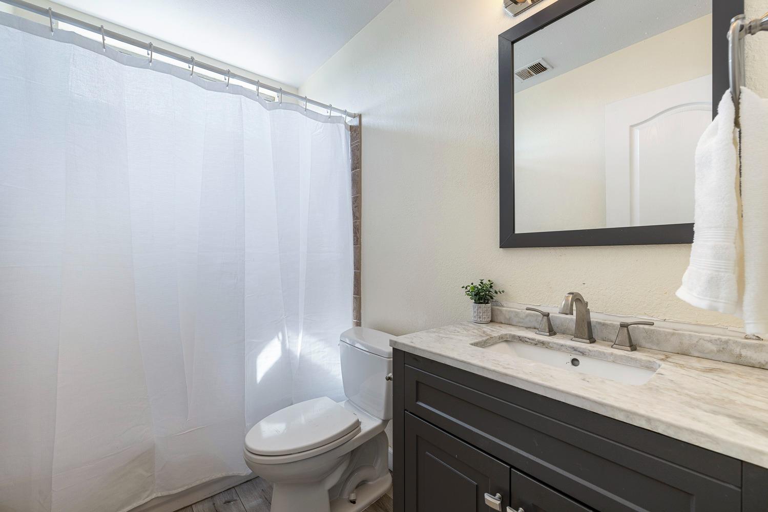 3232 Greenfield Avenue Clovis, CA 93611 - Photo 32 of 38 a bathroom with a granite countertop sink a toilet and a mirror