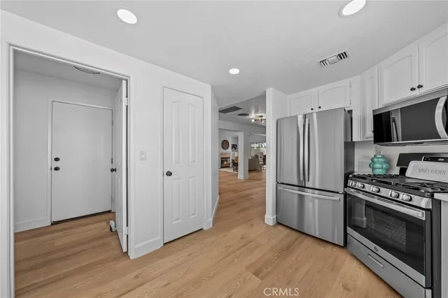 a kitchen with wooden floors appliances and cabinets
