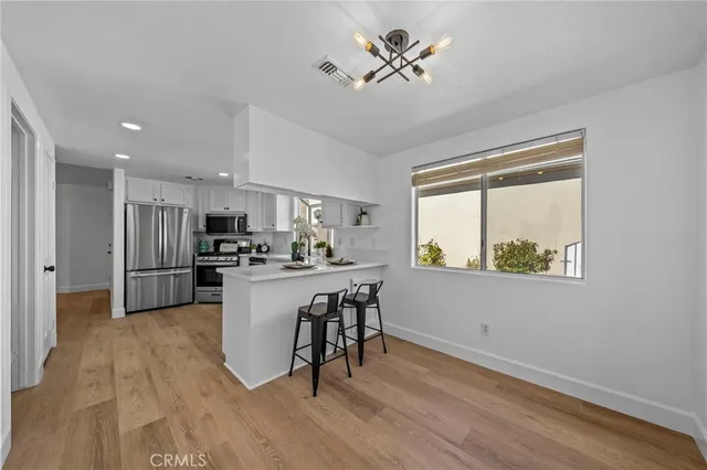 a kitchen with kitchen island wooden floors white cabinets and stainless steel appliances