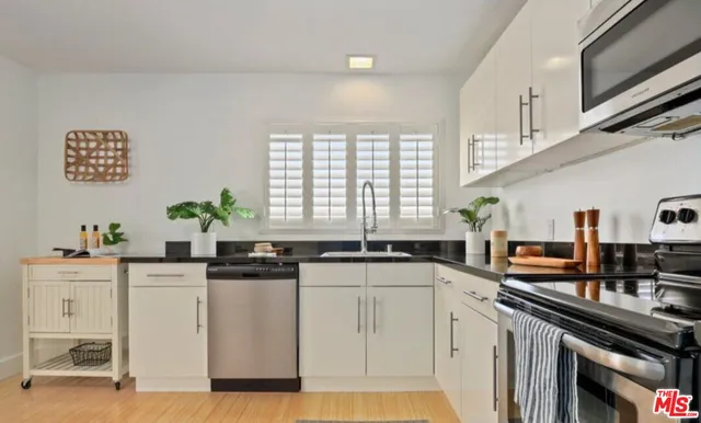 a kitchen with stainless steel appliances granite countertop a sink a stove a chimney a refrigerator and cabinets