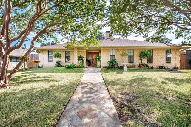 a front view of a house with a garden and trees