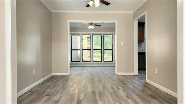 an empty room with wooden floor chandelier and windows