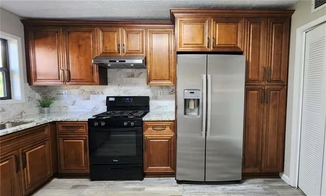 a kitchen with granite countertop a refrigerator and a stove