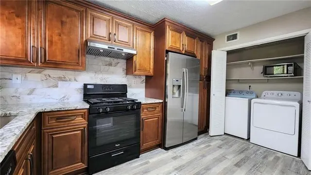 a kitchen with stainless steel appliances granite countertop a refrigerator and a stove top oven