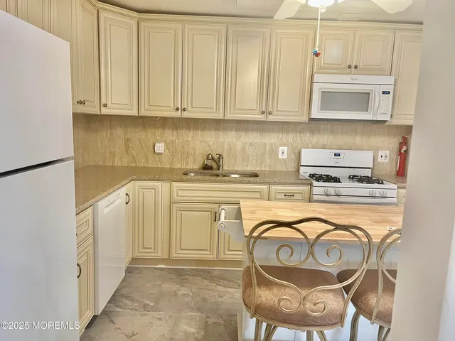 a kitchen with stainless steel appliances granite countertop a stove top oven a sink a dining table and chairs with white cabinets