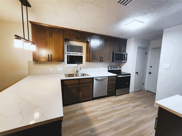 a large kitchen with kitchen island granite countertop a sink stainless steel appliances and cabinets