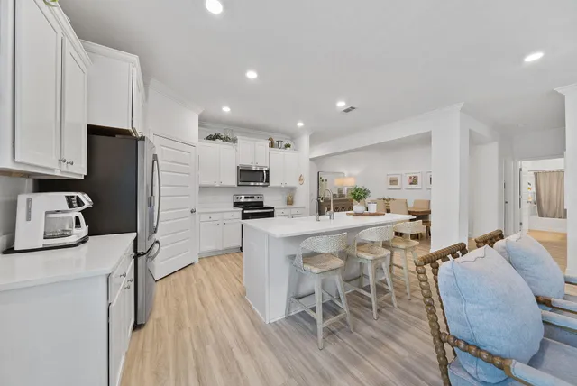 a kitchen with stainless steel appliances a table chairs refrigerator and a stove top oven