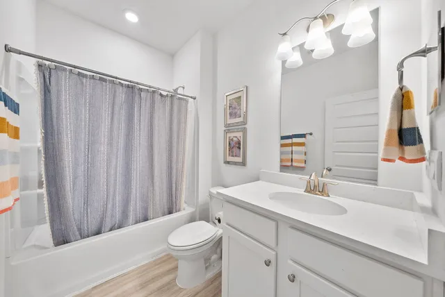 a bathroom with a sink a toilet a mirror and shower curtain