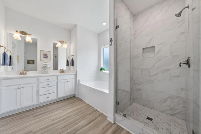 a spacious bathroom with a granite countertop sink a toilet a glass door shower and a mirror