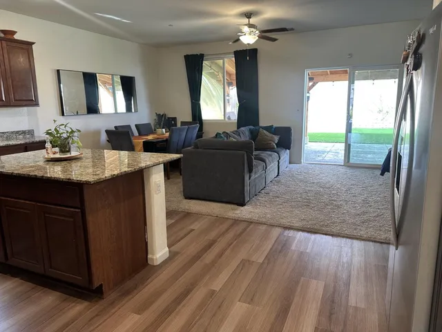 a living room with furniture a large window and wooden floor