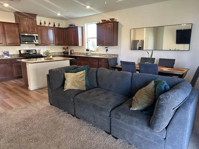 a living room with furniture kitchen and a wooden floor