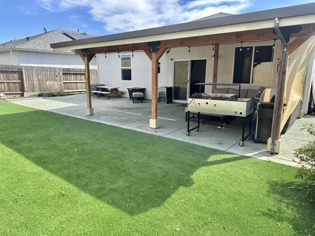 a backyard of a house with barbeque oven table and chairs