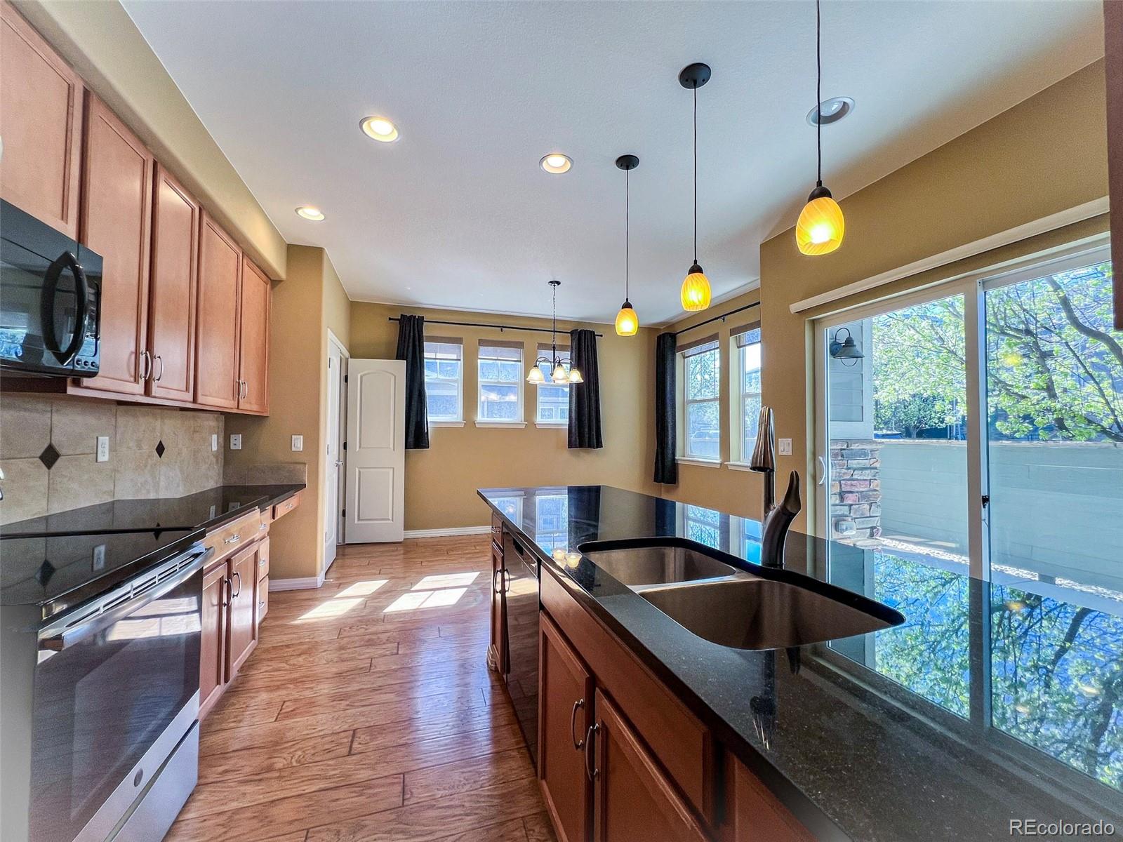 1524 Renaissance Drive Longmont, CO 80503 - Photo 7 of 23 a kitchen with stainless steel appliances granite countertop a sink a stove and a wooden floors