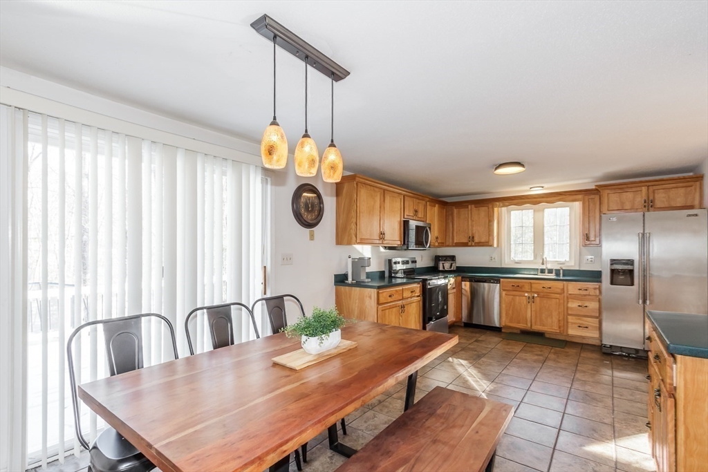 979 Hildreth Street Dracut, MA 01826 - Photo 14 of 39 a kitchen with stainless steel appliances granite countertop a stove top oven a sink dishwasher with a dining table and chairs