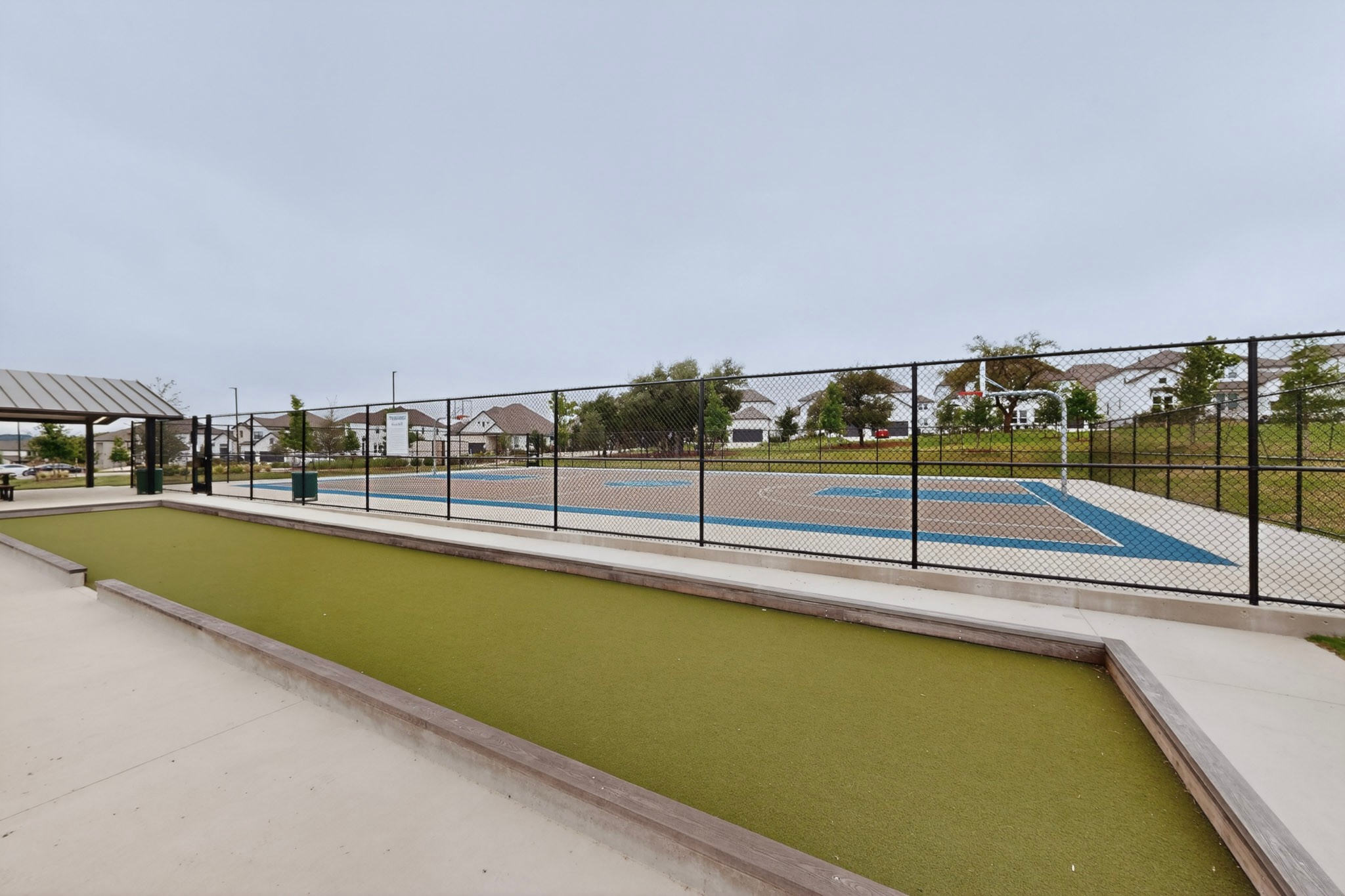 2308 Mondello Path Leander, TX 78641 - Photo 37 of 39 A community recreation area features a bocce court and a fenced basketball court with homes in the background.