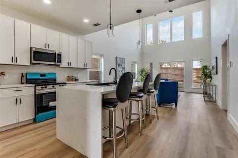 a kitchen with stainless steel appliances granite countertop a refrigerator a stove top oven a sink dishwasher and white cabinets with wooden floor