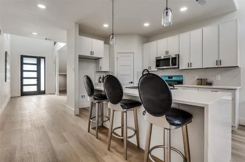 a kitchen with stainless steel appliances a stove a refrigerator a sink cabinets and wooden floor