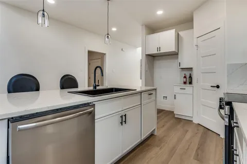 a kitchen with white cabinets and wooden floor