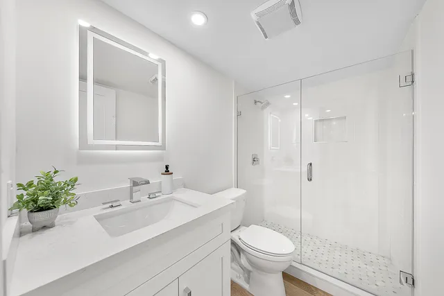 a bathroom with a sink toilet a mirror and shower