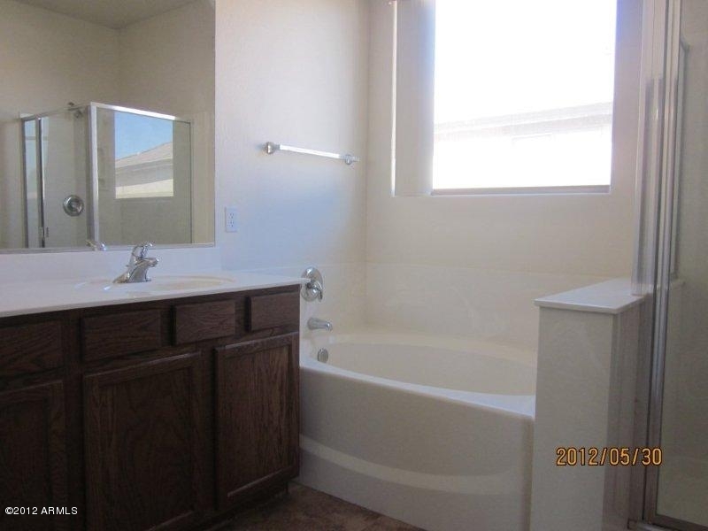 10213 West Payson Road Tolleson, AZ 85353 - Photo 9 of 24 a bathroom with a tub sink vanity and a mirror