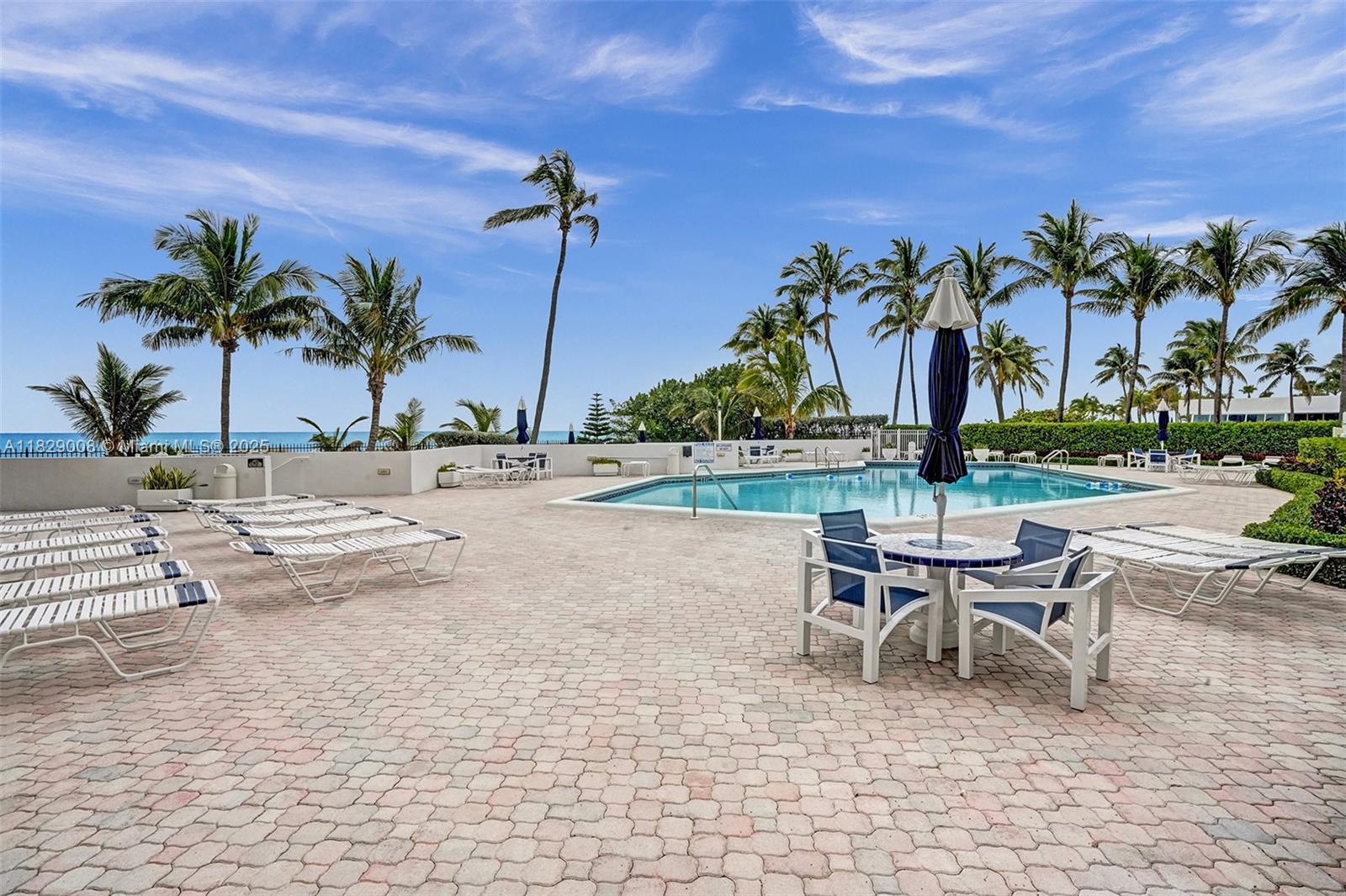 1340 South Ocean Boulevard, Unit 403 Pompano Beach, FL 33062 - Photo 57 of 74 a view of a swimming pool with a lounge chair and palm trees