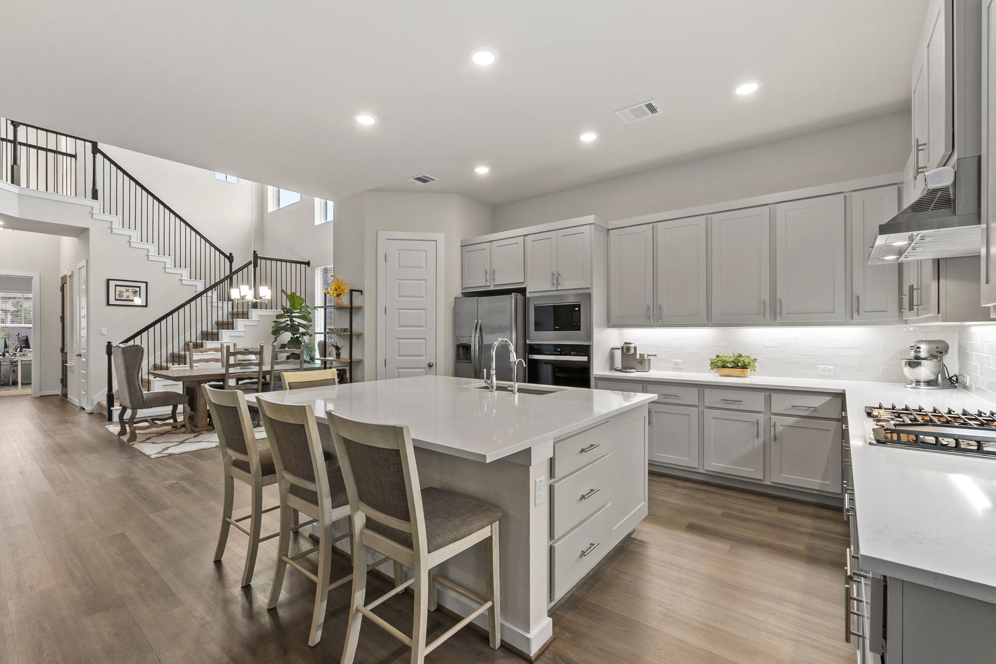 460 Constitution Way Kyle, TX 78640 - Photo 13 of 40 Spacious kitchen with a large central island, light wood-finish flooring, recessed lighting, stainless steel appliances, and ample grey cabinetry with undermount lighting