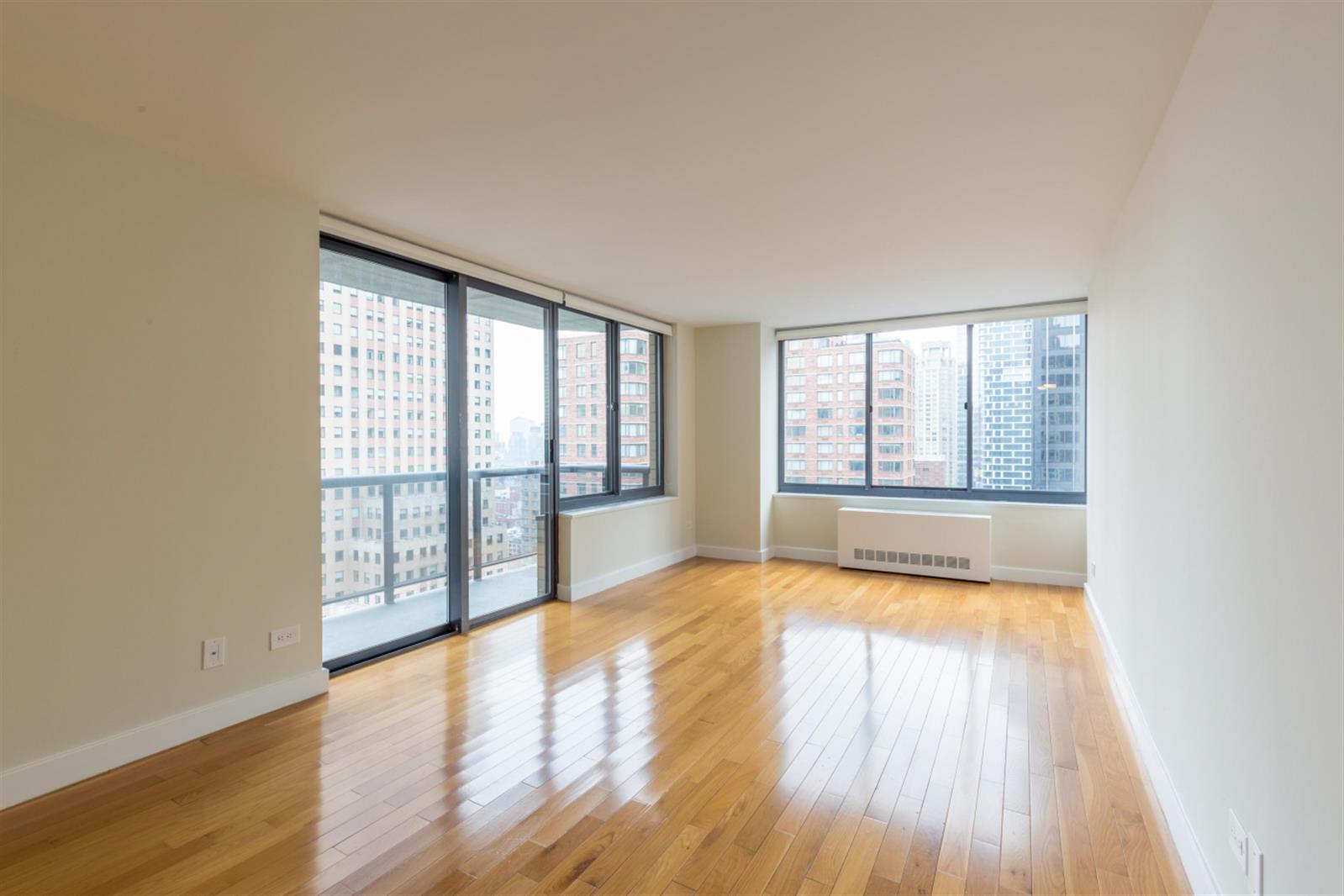 235 West 48th Street, Unit 43M Manhattan, NY 10036 - Photo 1 of 7 a view of an empty room with wooden floor and a window