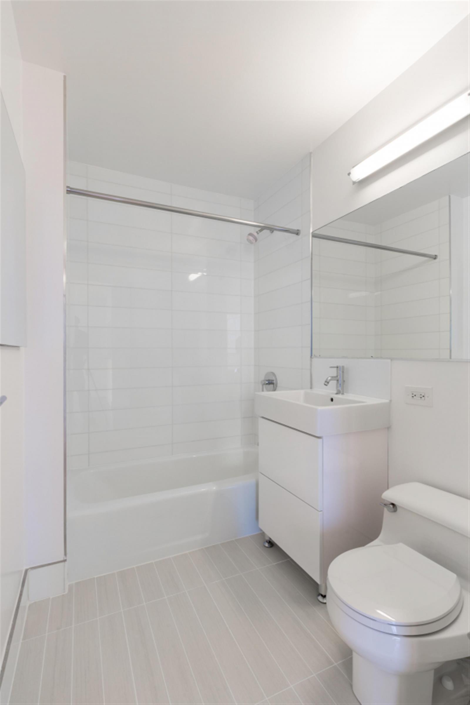 235 West 48th Street, Unit 43M Manhattan, NY 10036 - Photo 6 of 7 a bathroom with a sink a toilet and shower