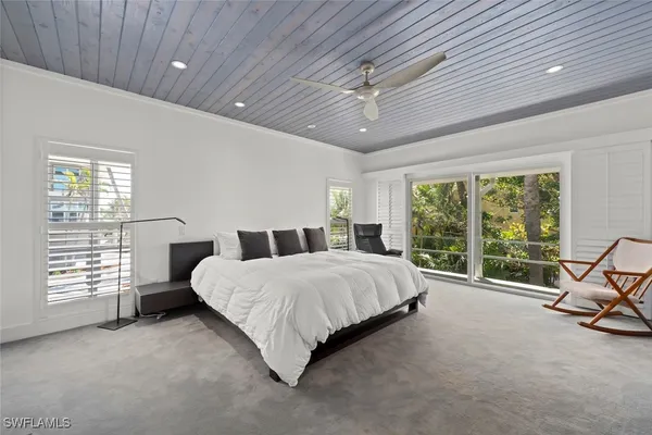 a spacious bedroom with a bed a chandelier and large window