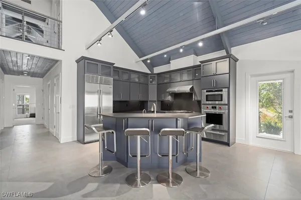 a kitchen with stainless steel appliances kitchen island granite countertop a table chairs refrigerator and microwave